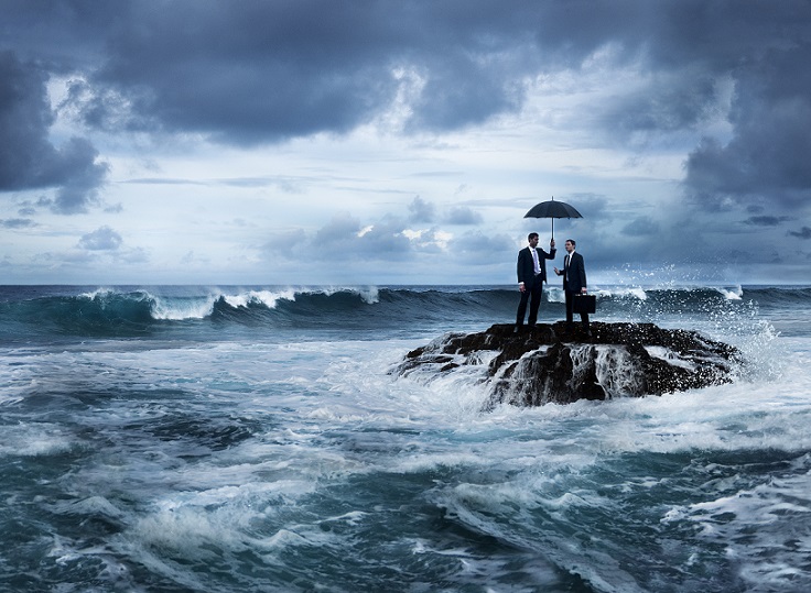 two men standing on rocks amidst turbulent seas