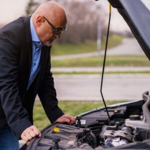 Businessman looking under bonnet of car to see why it stalled