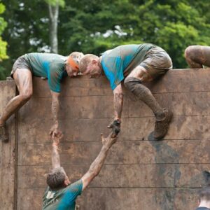 people climbing over wall as a metaphor to business survival or business growth in a survival race