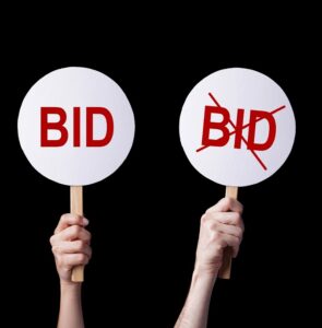 Business Concept of Bidders' hands lifting auction paddlesin a bid or no bid situation